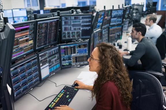 Financial analysts monitoring global markets on multi-screen trading workstations