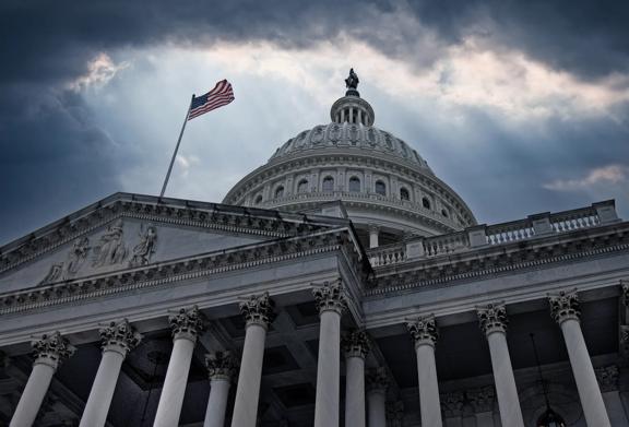 United States Capitol building in Washington, D.C. with American flag under dramatic sky