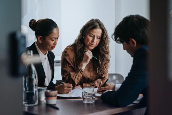 Team of financial professionals sitting in a conference room reviewing documents