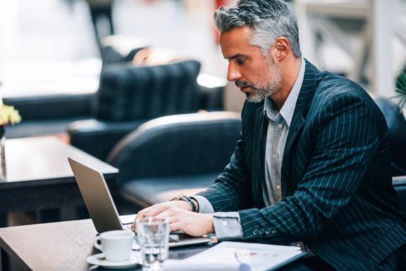 Professional working on a laptop at a table in a modern indoor setting.