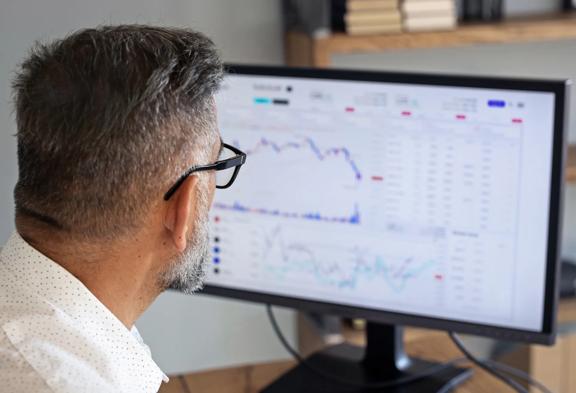 Business professional analyzing financial charts and market data on a computer screen