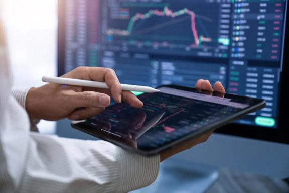 Professional using a tablet and smartphone to monitor live market data