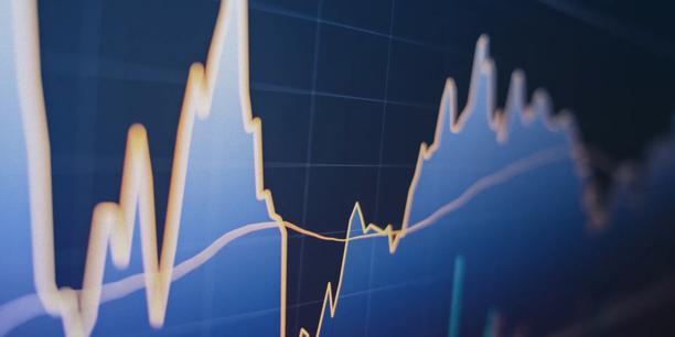 Close up view of a financial market chart displaying fluctuating price movements and trend lines on a blue grid background, representing market analysis, trading activity, and investment performance tracking.