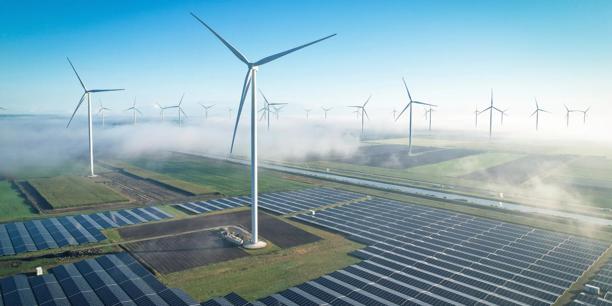 Turbinas eólicas e painéis solares gerando energia renovável em uma paisagem rural coberta por neblina baixa.