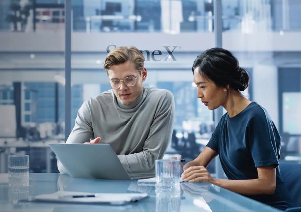 Two professionals collaborating in a modern office, working on a laptop and discussing business strategies