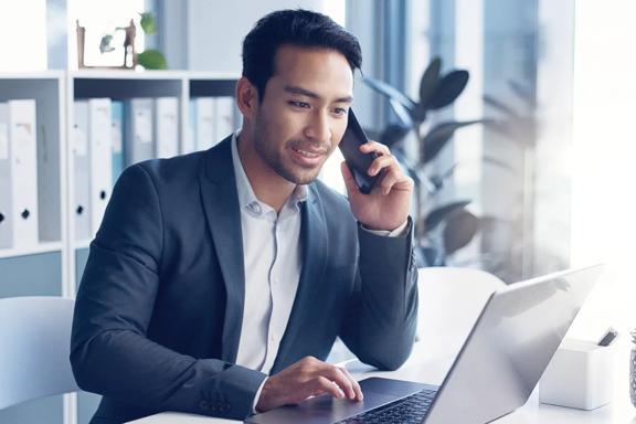 Professional speaking on the phone while working on a laptop