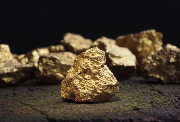 Raw gold nuggets on a textured surface, symbolizing StoneX’s expertise in precious metals trading and global commodity markets.