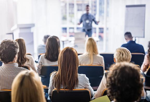 Audience attending a seminar or conference with a speaker presenting in the foreground
