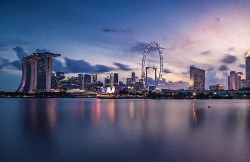 Singapore skyline at dusk with Marina Bay Sands, Singapore Flyer, and modern skyscrapers reflecting on the water