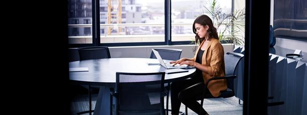 Businesswoman working remotely on a laptop in a modern office meeting room