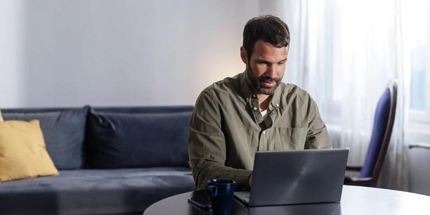 Person working on a laptop at a table in a home living space.