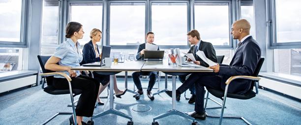 Business professionals in a modern meeting room, discussing reports and strategies around a conference table