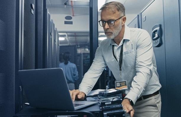 IT professional working in a server room, managing equipment in data racks