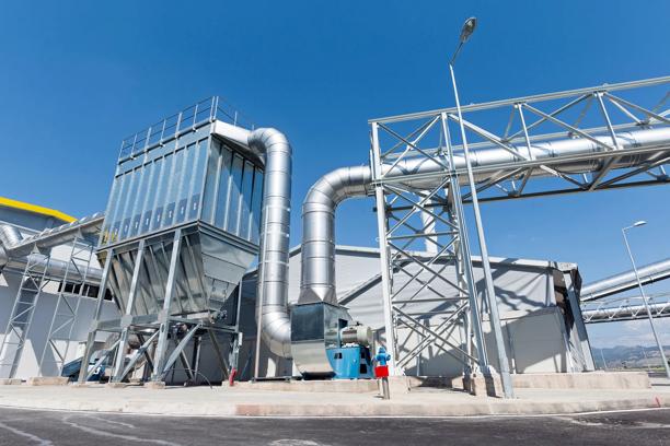 Vista externa de uma instalação industrial com grandes dutos de ventilação e equipamentos de filtragem