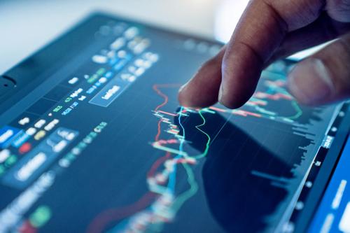 Finger interacting with a trading chart on a tablet showing real-time market data