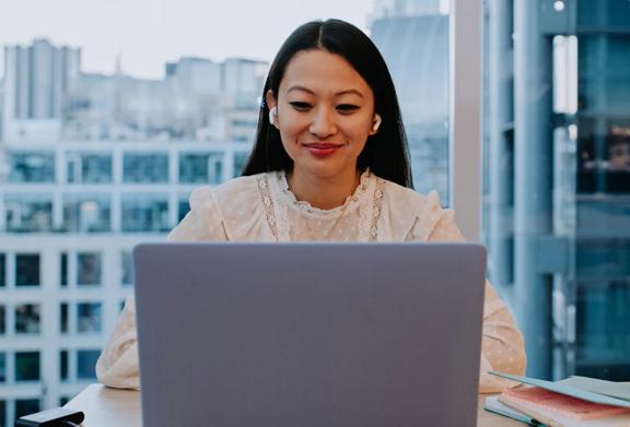 Mulher profissional usando um laptop e fones de ouvido durante uma reunião virtual em um escritório moderno