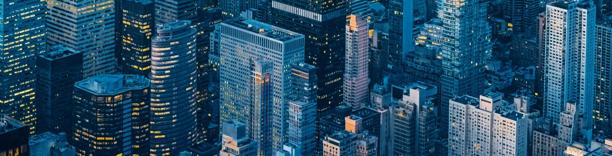 Aerial view of the New York City skyline at dusk featuring modern skyscrapers with glowing office lights.