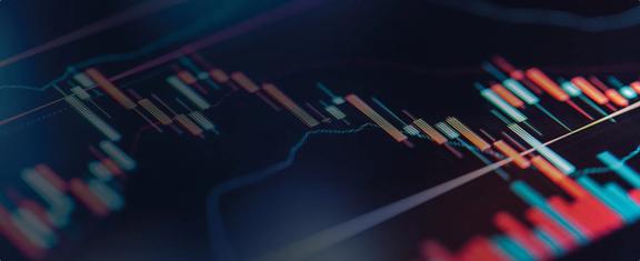 Close-up de gráficos do mercado financeiro exibindo padrões de candlestick, movimentação de preços e indicadores de negociação em uma plataforma digital.