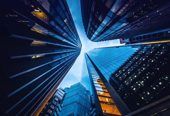 Upward view of modern skyscrapers in a financial district at dusk with glass reflections