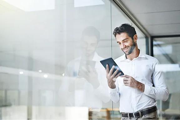 Profissional segurando tablet em ambiente corporativo com parede de vidro