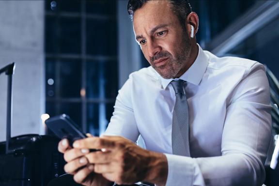  Professional trader wearing earbuds using smartphone