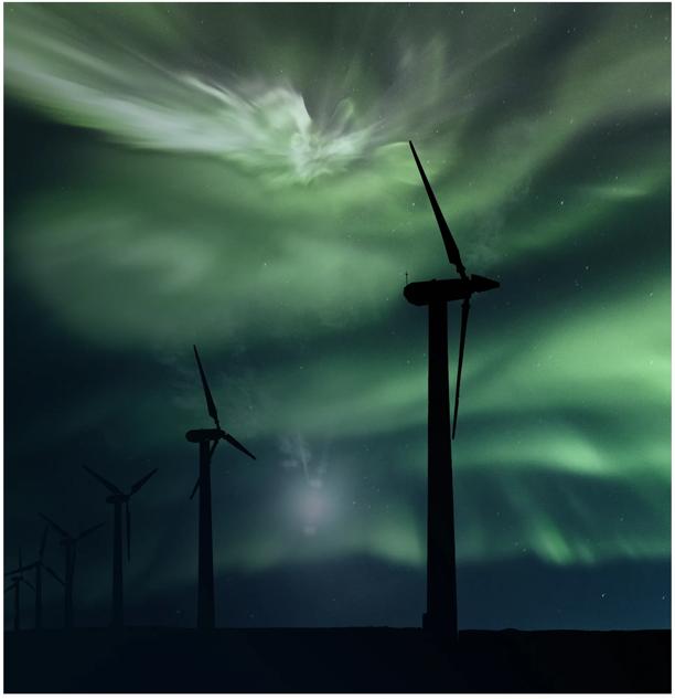 Wind turbines generating renewable energy under the northern lights.