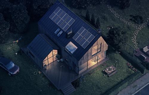 Vista aérea de uma casa moderna à noite, com painéis solares no telhado e iluminação interna quente