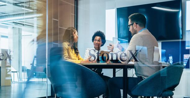 Team meeting in a modern office behind a glass wall with the StoneX logo visible