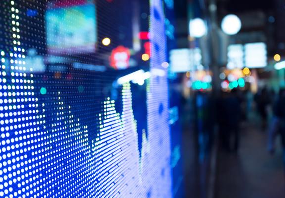 Digital stock market display with price chart on an LED screen in a city at night