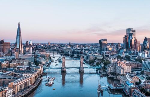 Aerial view of London skyline at sunset featuring Tower Bridge, the Shard, and modern skyscrapers along the River Thames