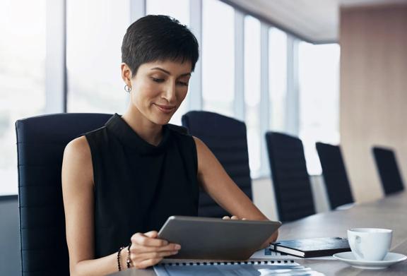 Mulher profissional analisando informações em um tablet digital em uma moderna sala de conferências