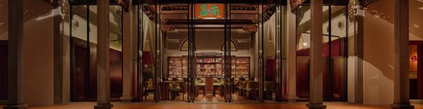 Elegant restaurant entrance featuring tall columns, warm ambient lighting, and a symmetrical interior design.