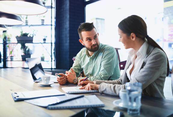 Businessman and businesswoman having a meeting at a modern workspace with documents and laptops