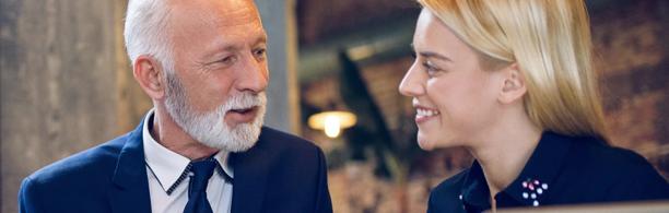 Senior businessman having a friendly conversation with a young professional woman in a modern office setting