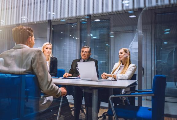 Corporate team having a business meeting in a modern glass-walled conference room