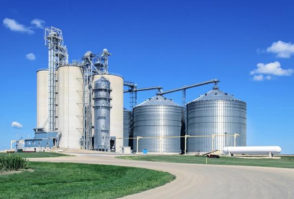 Large grain silos and storage facility in a rural agricultural setting under clear blue sky