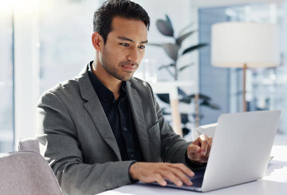 Profissional confiante trabalhando em um laptop em um escritório moderno e bem iluminado com luz natural