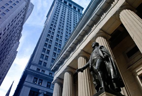 Statue in front of historic building with tall skyscrapers in New York City's Financial District