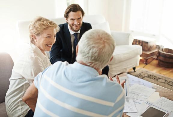 Financial advisor meeting with a happy senior couple at home.