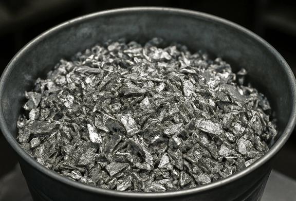 Container filled with raw silver flakes used in metal refining and industrial manufacturing