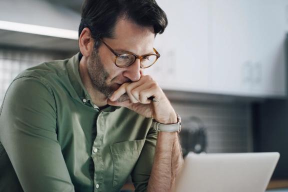 Professional using a laptop while reviewing financial information and market data in a modern office setting, representing investment research and trading analysis.