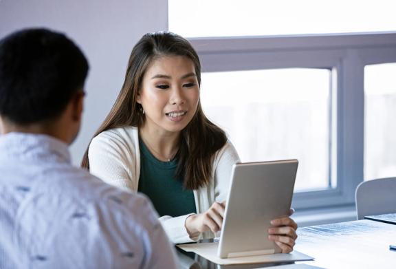 Professional woman presenting information on a digital tablet during a business meeting