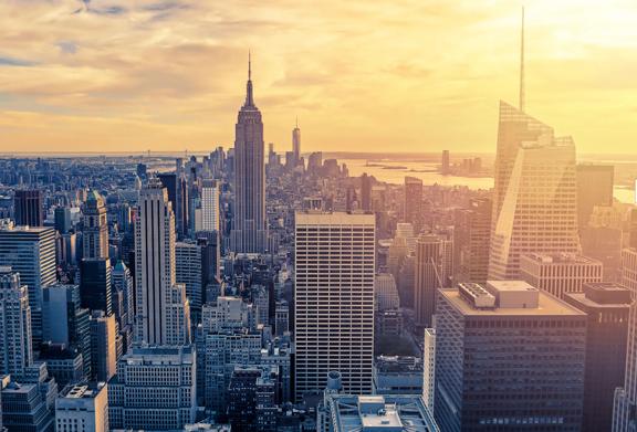 Panoramic view of New York City skyline during sunset, featuring the Empire State Building and modern skyscrapers