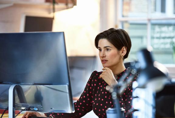 Focused businesswoman working at a desktop computer in a modern office setting