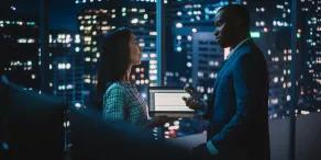 Professional analyzing global data on dual monitors in a modern office.