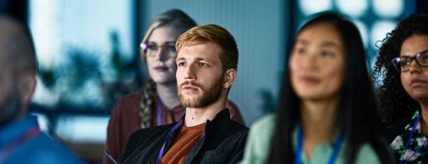 A diverse group of employees seated in a seminar setting during an Ability@StoneX awareness and education session, with faces blurred for privacy.