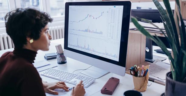 Focused professional analyzing financial charts and stock market data on a desktop monitor