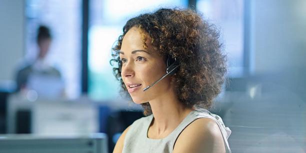 Profissional de atendimento ao cliente usando um headset e trabalhando em um computador em um ambiente de escritório.