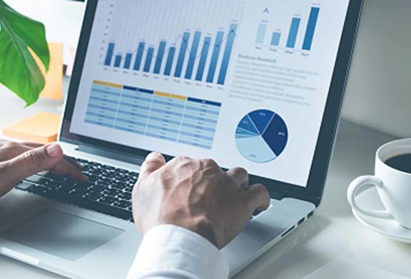 Businessperson reviewing charts and graphs on a laptop, representing financial analysis and data-driven decision-making.