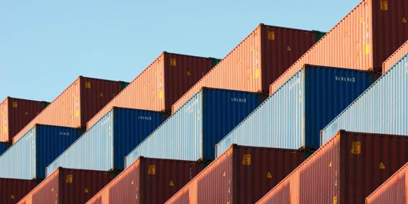 Stacked shipping containers arranged at a cargo terminal, representing global trade, supply chain management, freight transportation, and international logistics operations.